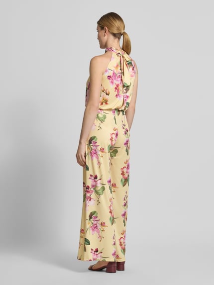 Frauenmodel trägt Regular Fit Jumpsuit mit floralem Allover-Print von V by Vera Mont in Creme mit buntem Blumenmuster, ärmellos, Nahtreißverschluss und Cut-Out am Rücken, Ganzkörperansicht Rückansicht.