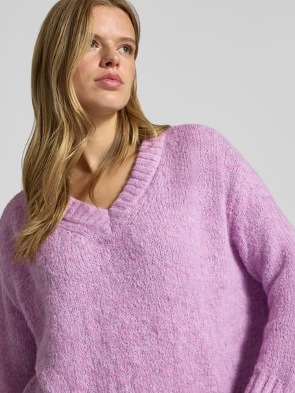 Frauenmodel trägt Pullover mit tiefem V-Ausschnitt von ONLY in fliederfarben, grob gestrickt, weiche Textur, Nahaufnahme Oberkörper. Damen Pullover von ONLY