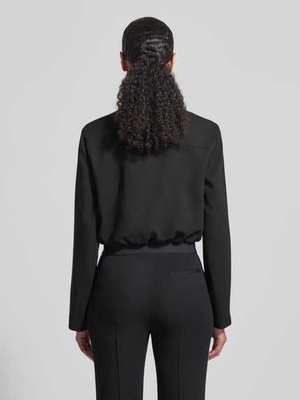 Modelka kobieca nosi Slim Fit Kurzblazer aus reiner Viskose Modell 'JOCALENA' von BOSS, jednolity kolor, czarna, krój slim fit, wykładany kołnierz, krótki krój, wyhaftowane logo, wytłaczane logo, aplikacja z logo, pas na plecach, zaszewki, zamek błyskawiczny dwustronny, długi rękaw, elastyczne wykończenie, boczne wpuszczane kieszenie, wiskoza, całe plecy, zdjęcie z tyłu, Ganzkörperansicht Rückansicht