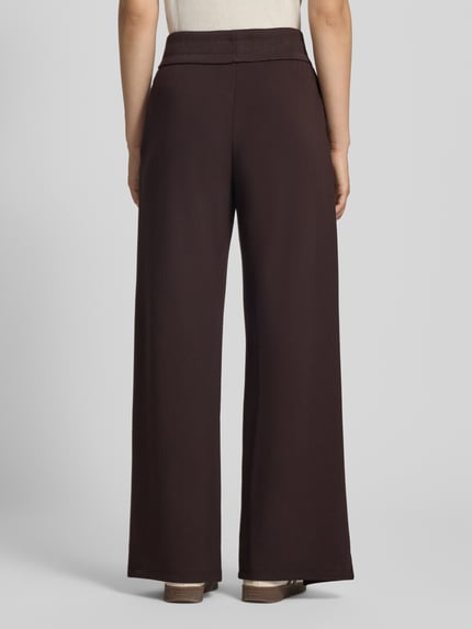 Frauenmodel trägt Straight Fit Sweatpants aus elastischem Viskose-Mix von Armani Exchange, dunkelbraun, Label-Detail, Bein-Schlitze, elastischer Bund, Ganzkörperansicht Rückansicht.