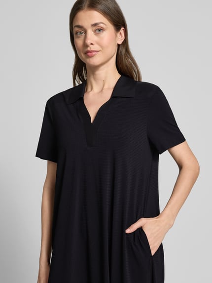 Frauenmodel trägt Midikleid mit Strukturmuster und Umlegekragen Modell 'JOSEPHINA' von Raffaello Rossi, Material-Mix mit Stretch-Anteil, V-Ausschnitt, Loose-Fit, schwarze Farbe, sichtbare Taschen, Nahaufnahme Oberkörper.