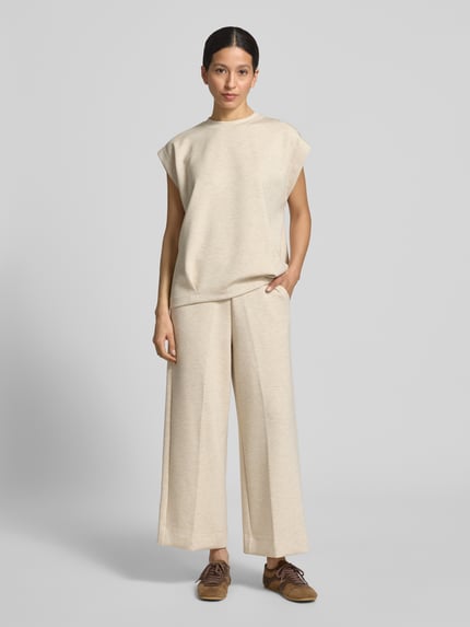 Vrouwenmodel draagt sweatpants uit viscosemix met labeldetail model 'Namara' van MOS MOSH in wide leg fit, met stretch, elastische band, zij-steekzakken, binnenbeenlengte maat S 69 cm, lichte beige textuur, effen kleuren, voorkant volledig zichtbaar, Ganzkörperansicht von vorne.