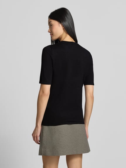 Frauenmodel trägt Regular Fit Pullover in Strick-Optik Modell "LULS" von ICHI, schwarz, kurzärmelig, Rundhalsausschnitt, Rückenansicht, Ganzkörperansicht Rückansicht.