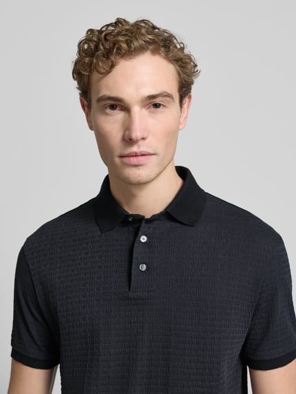 Männermodel trägt Regular Fit Poloshirt mit Strukturmuster von Emporio Armani aus reiner Baumwolle mit Polokragen, Knopfleiste, Nahaufnahme Oberkörper.