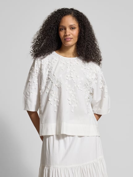 Frauenmodel trägt Bluse mit floraler Zier-Applikation von JAKE*S STUDIO WOMAN, weiß, lockere Passform, Rundhalsausschnitt, Ganzkörperansicht von vorne.