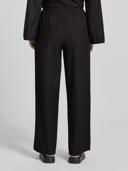 Frauenmodel trägt schwarze Stoffhose aus Viskose-Mix Modell 'PRISILLA' von Vila mit Wide Leg und Leinen-Viskose-Anteil, Ganzkörperansicht Rückansicht.