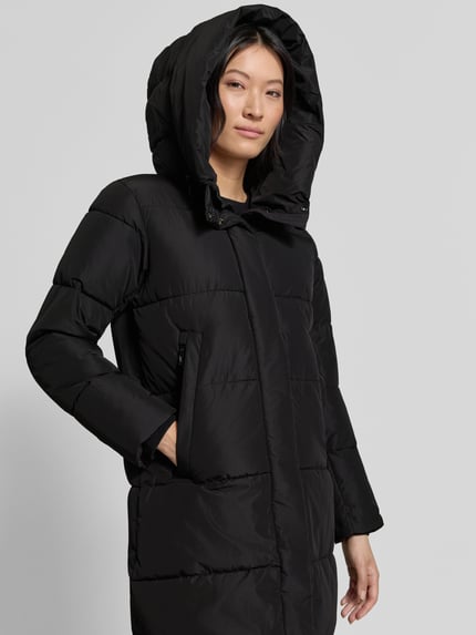 Frauenmodel trägt Regular Fit Mantel in Stepp-Optik Modell 'SOULANI' von khujo in Schwarz mit Kapuze, Eingrifftaschen; Nahaufnahme Oberkörper.