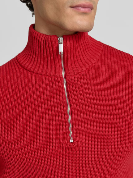Männermodel trägt Slim Fit Strickpullover aus reiner Baumwolle mit Troyer-Kragen von MCNEAL, Struktur in Rot, Nahaufnahme Oberkörper.