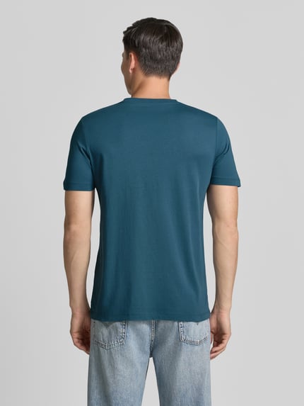 Männermodel trägt Regular Fit T-Shirt aus reiner Baumwolle von s.Oliver RED LABEL in Uni-Blau, glatte Jersey-Textur, Ganzkörperansicht Rückansicht.