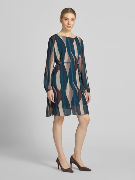 Frauenmodel trägt knielanges Kleid mit Bindegürtel Modell 'Sa44raa' von ZABAIONE aus Chiffon, Allover-Look, Plisseefalten, Rundhalsausschnitt, gemusterte Farben in Blau, Beige und Braun, gerader Schnitt, Ganzkörperansicht von vorne.