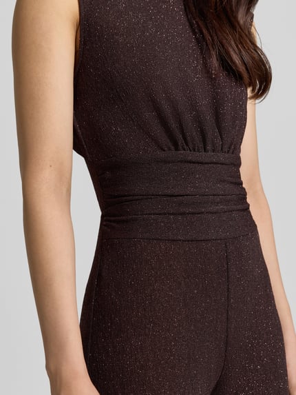Frauenmodel trägt Jumpsuit mit Raffungen von Rinascimento in Dunkelbraun mit Glanz, taillierte Passform, Material-Mix, Nahaufnahme Oberkörper.