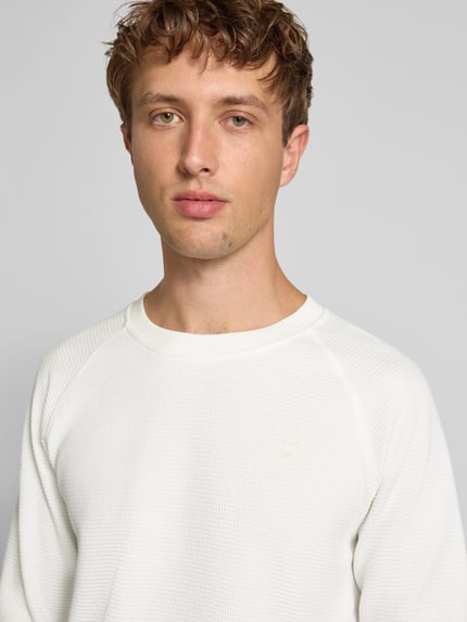 Mannenmodel draagt Longsleeve mit Strukturmuster und Logo van G-Star Raw in regular fit katoenmix met logo en ronde hals, Nahaufnahme bovenlichaam.