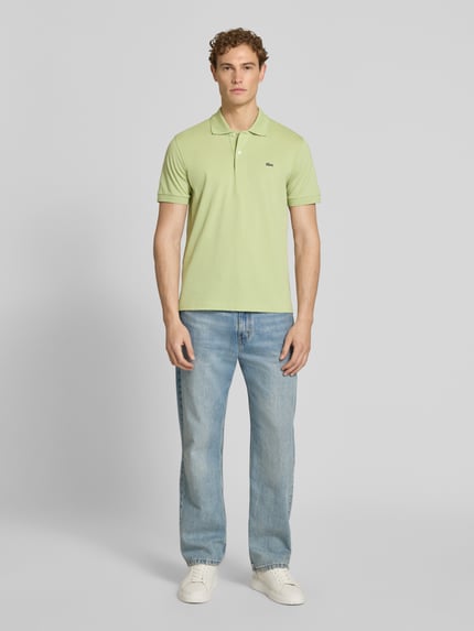 Männermodel trägt Regular Fit Poloshirt aus Baumwoll-Mix von Lacoste in Hellgrün, unifarben, Logo-Detail, Piqué-Textur, Ganzkörperansicht von vorne.