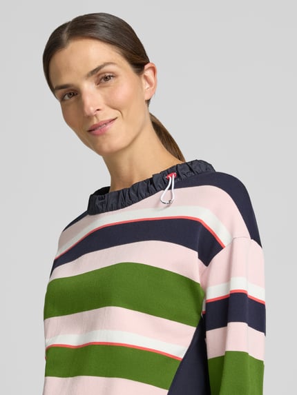 Kobiece model prezentuje Relaxed Fit Sweatshirt aus Viskose-Mix od Marc Cain, Mieszanka wiskozy, krój relaxed fit, tunel, stójka, z długim rękawem, elastyczne wykończenia, długość tyłu w rozmiarze 36: 55 cm, długość rękawów w rozmiarze 36: 51 cm, wielokolorowe paski, tekstura miękka, widok z przodu, zbliżenie na górną część ciała.