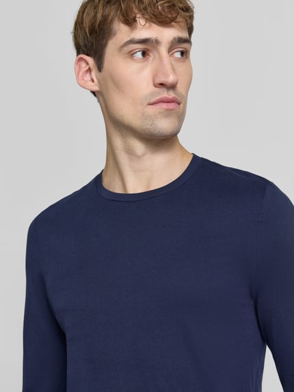 Männermodel trägt Slim Fit Longsleeve aus puur katoen von Christian Berg Men in effen donkerblauw met ronde hals, Nahaufnahme Oberkörper. Ruglengte bij maat M: 70 cm, heren shirt met lange mouwen, omzoomde boorden.