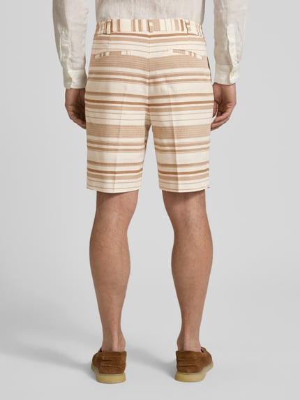 Männermodel trägt Shorts mit Strukturmuster und Eingrifftaschen Modell 'Pino' von Zuitable, Baumwoll-Mix, Straight, Ganzkörperansicht Rückansicht. Bundweite bei Größe M 41 cm, Innenbeinlänge 21 cm, beige und braune Streifen, Gesäßleistentaschen.