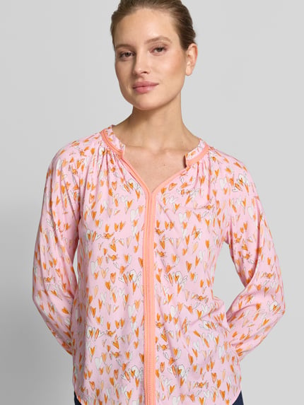 Frauenmodel trägt Regular Fit Bluse aus Viskose mit V-Ausschnitt von Emily Van den Bergh in Rosa mit Allover-Herzmotiv, Nahaufnahme Oberkörper.