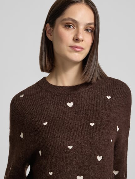 Frauenmodel trägt Strickpullover mit Stitchings und Rundhalsausschnitt von Apricot in Braun mit Woll-Anteil, Nahaufnahme Oberkörper.