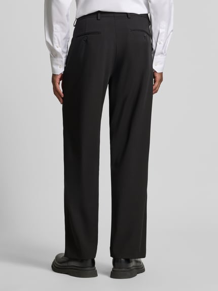 Männermodel trägt schwarze Loose Fit Anzughose mit Gürtelschlaufen Modell 'LOOSE-LIAM' von Selected, Herren Anzughose, Ganzkörperansicht Rückansicht.