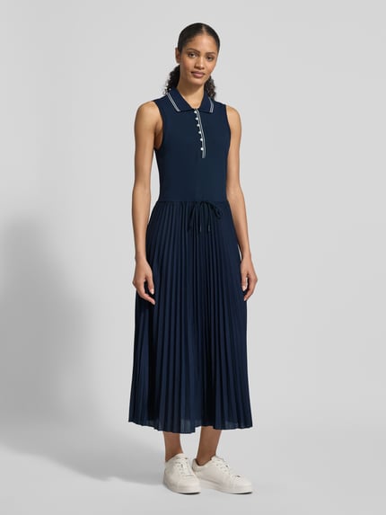 Vrouwenmodel draagt 'Tailliertes Freizeitkleid aus Baumwoll-Mix' van Tommy Hilfiger, effen blauw, getailleerde fit, plissé, midi, polokraag, katoenmix, knoopsluiting, brede bandjes, geheelvooraanzicht.