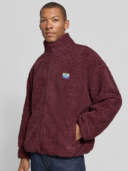 Männermodel trägt unifarbene Sweatjacke mit Fleece-Struktur Modell 'HOKTOWN' von AMERICAN VINTAGE, Struktur-Oberfläche, Ganzkörperansicht von vorne.