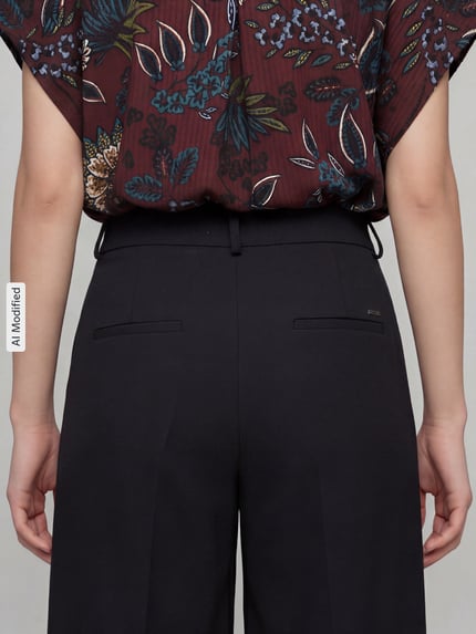 Frauenmodel trägt Weite Hose aus Viskose-Mix Modell 'MELLI S' von Brax in Schwarz, glatte Textur, Ganzkörperansicht Rückansicht, Damen Weite Hose von Brax.