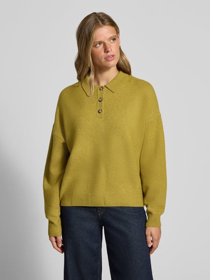 Frauenmodel trägt Oversized Strickpullover mit Polokragen von REVIEW, gelb, lockerer Schnitt, Allover-Look, Knopfleiste, Nahaufnahme Oberkörper.