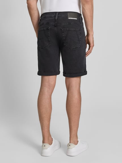 Männermodel trägt Slim Fit Jeansshorts aus katoenmix model 'NAAILO' van Armedangels met denimlook, labelpatch, riemlussen, knoop- en ritssluiting, omslag aan de pijpen, 5-pocketmodel, kleur donkergrijs, materiaal katoenmix, ganzkörperansicht rückansicht.