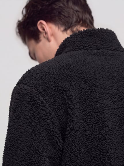 Männermodel trägt Sweatshirt mit Logo-Detail Modell 'Derylong' von HUGO aus schwarzem Fleece mit Struktur, Detailaufnahme Rückansicht.