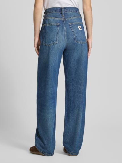 Modelka prezentuje Tapered Fit Jeans im 5-Pocket-Design von Carhartt Work In Progress z bawełny ekologicznej, stylizowane na denim, krój tapered fit, zapięcie na guzik i zamek błyskawiczny, 5 kieszeni, szerokość w rozmiarze 27: 38 cm, długość wewnętrzna nogawki: 78 cm, widok całej sylwetki z tyłu