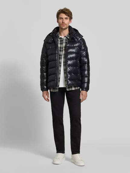 Männermodel trägt Steppjacke mit abnehmbarer Kapuze Modell 'FLORIAN' von Save The Duck in Schwarz mit Reißverschlusstaschen, Ganzkörperansicht von vorne.