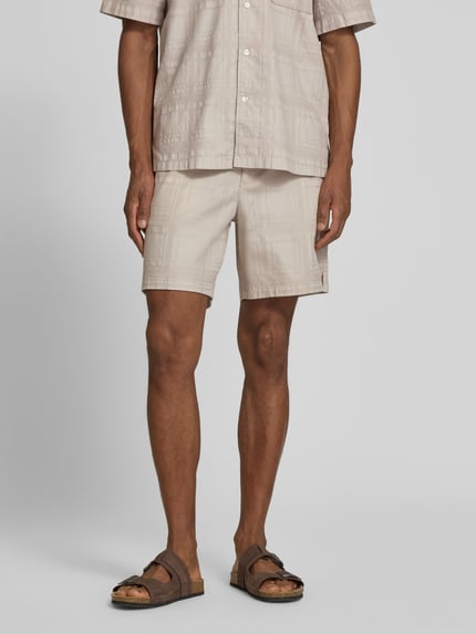 Męski model nosi Tapered Chinoshorts aus reiner Baumwolle Modell 'SANDREW_6_SHORTS' von BOSS Orange, efekt: jednolity kolor, faktura, krój tapered, tunel, elastyczny ściągacz, zakończenie nogawek z rozcięciem z boku, materiał: bawełna, Ganzkörperansicht von vorne.