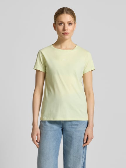 Vrouwenmodel draagt Slim Fit T-Shirt uit pure katoen model 'ELOVE_EMBRO' van BOSS Orange in effen lichtgeel, ronde hals, korte mouw, label-stiksel detail, voorkant, hele lichaamsaanzicht.