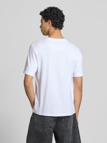 Männermodel trägt Regular Fit T-Shirt mit Statement-Print Modell 'Eres' von Jack & Jones aus reiner Baumwolle, Ganzkörperansicht Rückansicht.