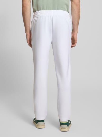 Mannelijk model draagt Tapered Sweatpants met katoen van Lacoste Sport in effen wit, scuba-materiaal, elastische tailleband, achteraanzicht volledige lichaamsopname.