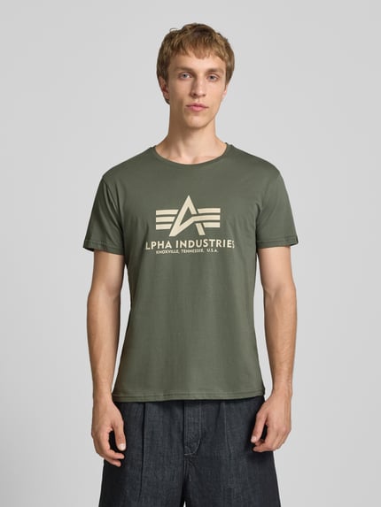 Männermodel trägt T-Shirt mit Logo und Rundhalsausschnitt von Alpha Industries aus reiner Baumwolle, Regular-Fit, grün, Ganzkörperansicht von vorne.