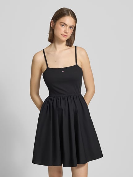 Frauenmodel trägt Tailliertes Freizeitkleid aus reiner Baumwolle von Tommy Jeans in Schwarz mit geradem Saum, Mini-Länge, Logo-Stitching, Spaghettiträgern und seitlichen Eingrifftaschen, unifarbene Optik, Nahaufnahme Oberkörper.