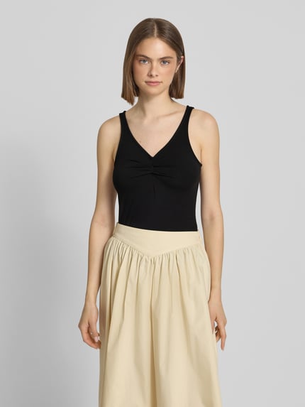 Frauenmodel trägt Slim Fit Top aus Viskose-Mix Modell 'MALIVA' von Pieces, unifarben schwarz, V-Ausschnitt, Ganzkörperansicht von vorne.