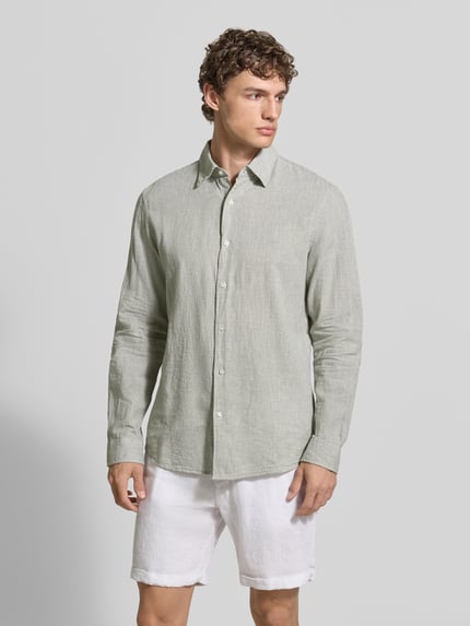 Męski model nosi Regular Fit Freizeithemd aus Leinen-Baumwoll-Mix od MCNEAL, jasnoszare z długim rękawem, kentkragen, listwa guzikowa, długość tyłu w rozmiarze M: 74 cm, szerokość w rozmiarze M: 48 cm, długość rękawa w rozmiarze M: 66 cm, widok całej sylwetki od przodu.
