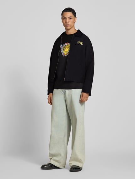 Männermodel trägt Blouson aus Baumwoll-Mix von Kenzo in Schwarz mit Umlegekragen, gerader Passform, Eingrifftaschen; Ganzkörperansicht von vorne.