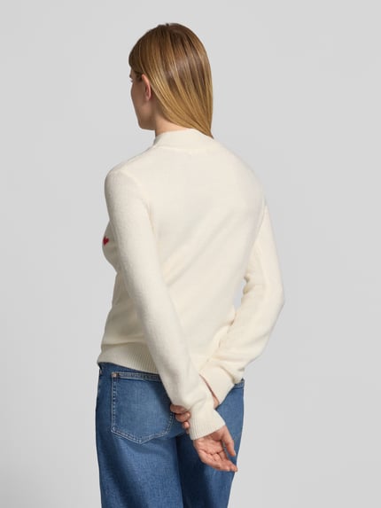 Frauenmodel trägt Strickpullover im Allover-Look mit Stehkragen von Christian Berg Woman in Creme, kombiniert mit blauer Jeans, Ganzkörperansicht Rückansicht. Material-Mix mit Stretch-Anteil, Slim Fit, Rückenlänge 56 cm, Ärmellänge 64 cm.