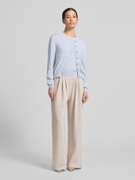 Frauenmodel trägt Strickshirt mit Rundhalsausschnitt Modell 'Arabella' von GUIDO MARIA KRETSCHMER WOMAN im Lyocell-Mix mit Seiden-Anteil, Regular-Fit, hellblaue Farbe, glatte Textur, kombiniert mit heller Hose, Ganzkörperansicht von vorne.