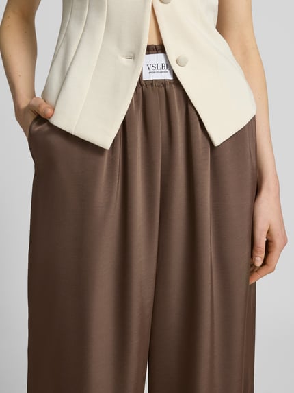 Kobiece modelka nosi Wide Leg Stoffhose aus Baumwoll-Mix Modell 'LUCA' od VILLA SOPHIE, efekt: jednolity kolor, mieszanka bawełny, krój wide leg, naszywka z logo, elastyczny ściągacz, wpuszczane kieszenie, zbliżenie na górę spodni