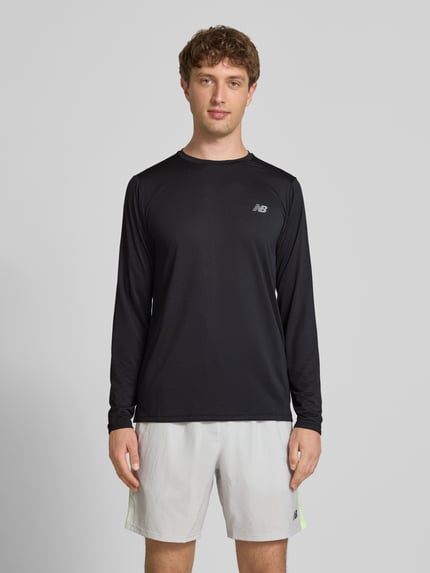 Męski model nosi Funktionsshirt mit Rundhalsausschnitt und Logo od New Balance, czarny kolor, krój regular fit, longsleeve, nadruk logo, długość tyłu w rozmiarze M: 72 cm, pełny widok z przodu