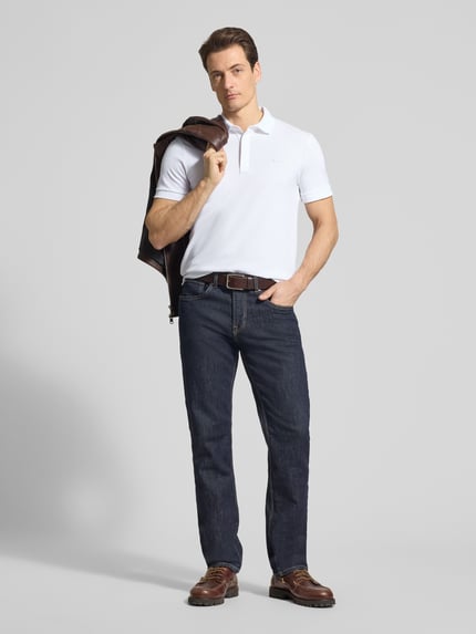 Männermodel trägt Regular Fit Poloshirt aus Baumwoll-Mix von Lacoste, Optik: Unifarben, Piqué-Struktur, Ganzkörperansicht von vorne.