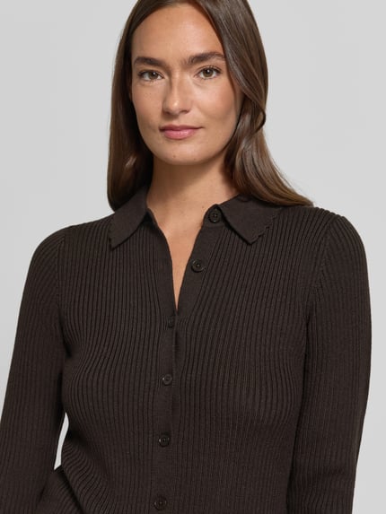 Frauenmodel trägt Cardigan aus Lanawolle mit Polokragen Modell 'ARHANYA' von DRYKORN, braun, Ripp-Optik, Nahaufnahme Oberkörper.