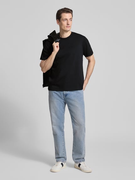 Männermodel trägt T-Shirt mit Rundhalsausschnitt von CK Calvin Klein in Schwarz, Reine Baumwolle, Regular-Fit, Logo, Ganzkörperansicht von vorne.