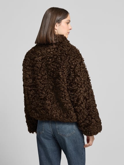 Vrouwenmodel draagt Jacke aus Kunstfell van closed, donkerbruin, recht pasvorm, opstaande kraag, ruglengte 60 cm, schouderbreedte 56 cm, borstwijdte 59 cm, mouwlengte 66 cm, volledig doorlopende knoopsluiting, textuur met imitatiebont, Ganzkörperansicht achteraan.