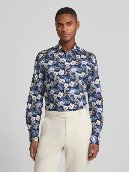 Männermodel trägt Slim Fit Businesshemd aus Baumwoll-Mix mit Kentkragen von OLYMP Level Five mit floralen Mustern, Ganzkörperansicht von vorne.