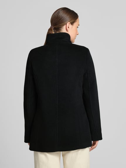 Frauenmodel trägt Jacke mit Stehkragen und Eingrifftaschen von FUCHS SCHMITT, schwarze A-Linie, Material-Mix mit Woll-Anteil, Ganzkörperansicht Rückansicht.